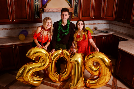 New 2019 Year is coming. Group of cheerful young people carrying gold colored numbers and have fun at the party.の写真素材