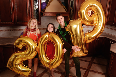 New 2019 Year is coming. Group of cheerful young people carrying gold colored numbers and have fun at the party.の写真素材