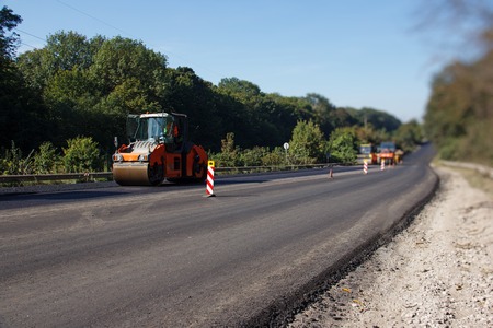 Carrying out repair works: asphalt roller stacking and pressing hot lay of asphalt. Machine repairing road.の写真素材