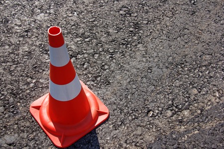 traffic cone, with white and orange stripes on gray asphalt, copy space.の写真素材