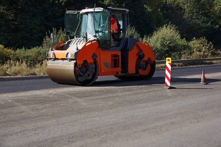 Carrying out repair works: asphalt roller stacking and pressing hot lay of asphalt. Machine repairing road.の写真素材