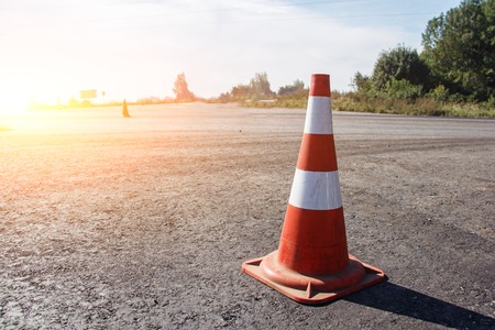 traffic cone, with white and orange stripes on gray asphalt, copy space.の写真素材