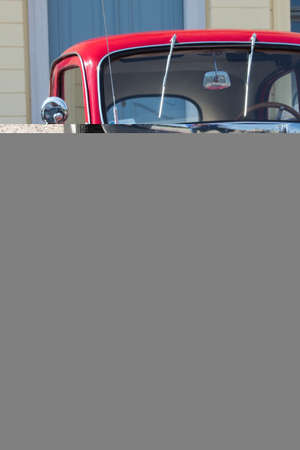 A vertical shot of a red old american car on the street