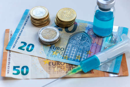 50 euro bank note and 20 euro note with injection syringe with blue medical liquid medicine wait for a rich patient to heal his diseases if he pays much money for his health careの写真素材
