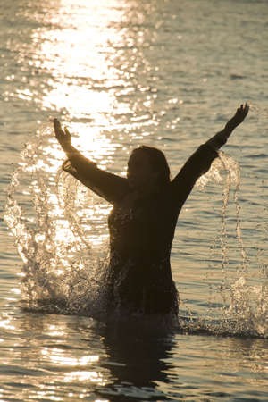 Wet woman playing with water in sunriseの写真素材