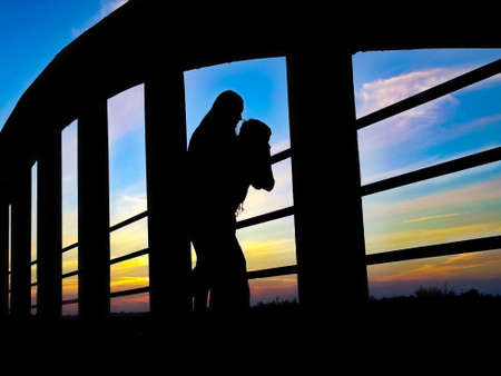 young people watching the sunset from a bridgeの写真素材