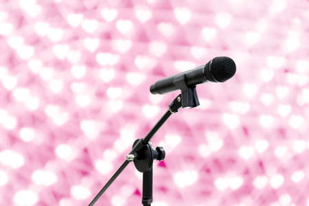 Microphone close up shot on blur heart bokeh Pink background beautiful romantic or glitter lights heart soft pastel shadeの写真素材