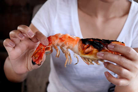 Hand are holding shrimp big size, Shrimp grill in hand, Seafood Prawn dinner, Cooked grilled shrimp or eating shrimp peeledの写真素材