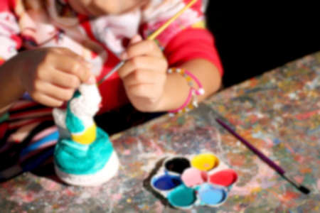 blurred kids coloring fun night time, children painting ceramic statues in whiteの写真素材
