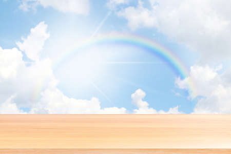 empty wood table floors on rainbow and blue sky background, wood table board empty front rainbows rings circle on sky, wooden plank blank over colorful rainbow in the sky for mock up display productsの写真素材