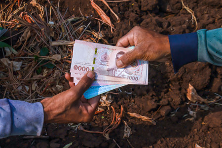 money banknote thai baht in the hand farmer or worker man, giving money and land trading concept,...