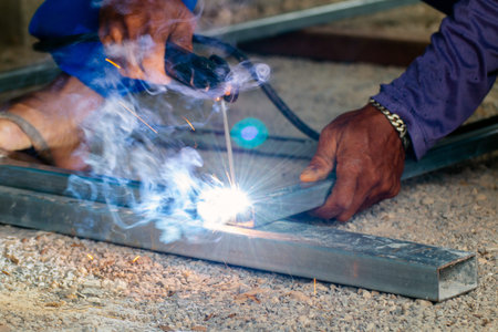 welder and welding sparks, construction and metal work industrial concept, metal welding with...