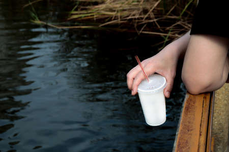 plastic water cup in hand holding at river, plastic garbage waste cup in handの写真素材