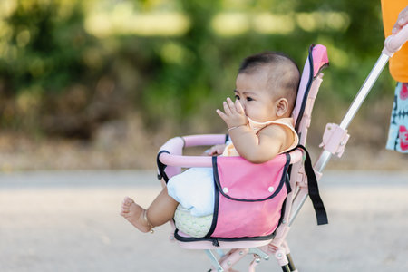 happy baby girl asia in stroller outdoor, asia baby cute 4-5-6 months, activity outdoor of family conceptの写真素材