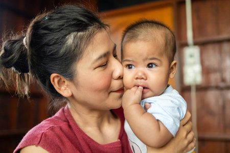 mom and baby are playing on bed happy, asia baby cute 4-5-6 months, activity outdoor of family conceptの写真素材