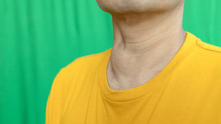 Thyroid gland inflammation at neck, goiter, throat cancer, sore throat and cough, man with neck pain on green, neck health problems conceptの写真素材