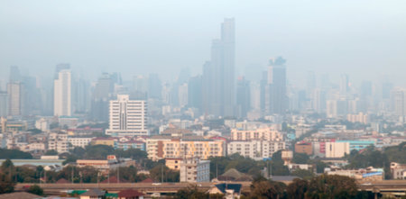 Blurred view of Bangkok cityscape covered in smog, seen from above. tall buildings hidden in haze, Perfect for background use or depicting air pollution in urban environmentsの写真素材