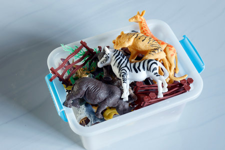 Plastic animal toys in storage box, Assorted plastic animal toys in a white storage box, including zebra, giraffe, tiger, and rhino figures, representing childhood play, learning, and imaginationの写真素材