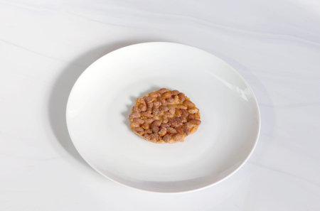 Peanut brittle placed on a white plate with a minimal light background, suitable for food, dessert,...