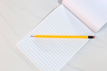 Yellow pencil on lined notebook in flat lay style. Minimal and clean composition with copy space....