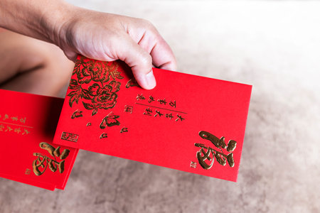 Hands holding red envelopes hongbao for giving, Angpao with gold (Fu) symbol, symbolizing blessings,...
