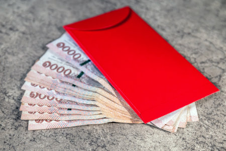 Red envelopes angpao with golden (Fu) symbol and thai banknotes, Hongbao, representing wealth, fortune, and prosperity during Lunar New Year celebration, close-upの写真素材
