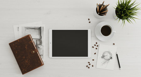 A tablet, coffee, and a notebook on a white table showing a top view of a modern workspace with digital tablet, sketchbook, coffee cup, and minimalist decorの素材