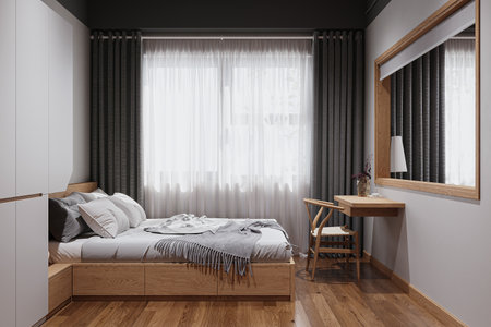 A minimal bedroom placed in a studio apartment with a wooden bed, chair, and wall-attached table.の写真素材