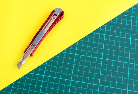 Box Cutter Knife Cutting yellow paper on cutting matの写真素材