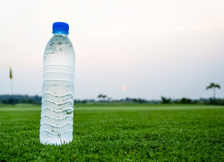 Cold Drinking water bottle on beautiful green fieldの写真素材