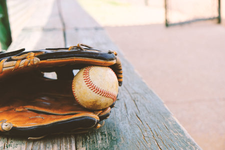 Baseball in glove laying on dugout bench before game.  Player equipment for the sport.