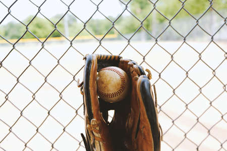 Old used ball in glove, view from team dugout.  Baseball field in background.の写真素材