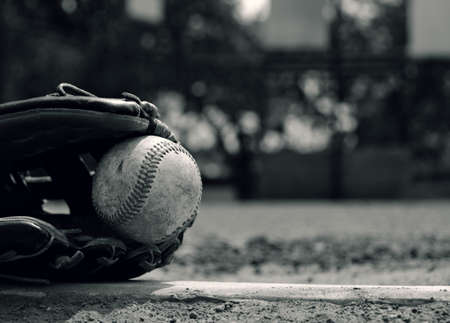Baseball in glove laying on pitcher's mound of ball field.  Vintage style sport graphic in black and white.の写真素材