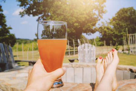 Summer scenic day relaxing with feet up outdoors, beer in hand for refreshing adult drink.の写真素材