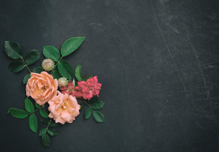 Elegant vintage style floral arrangement with roses and greenery against black grunge texture...