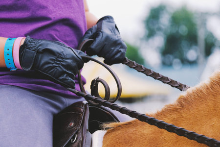 English style rider with leather gloves and reins for horseback riding at show closeup.の写真素材