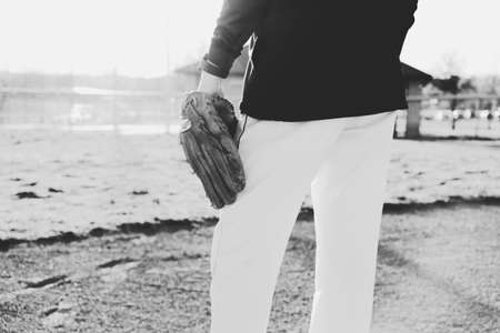 Close up of baseball player lifestyle with athlete on field with glove and uniform in black and white.の写真素材