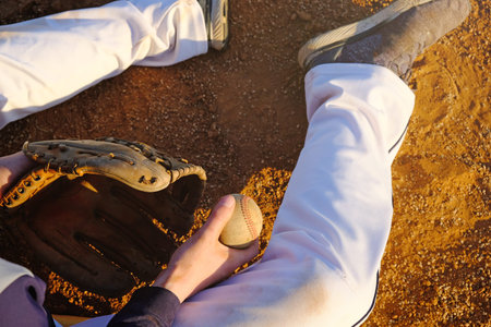 Player sitting on field with ball and glove for baseball lifestyle.