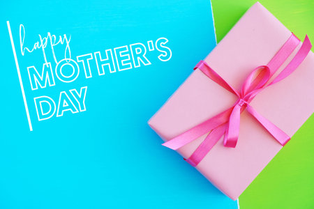 Happy Mother's day message with pink gift box on bright blue and green background for holiday.の写真素材