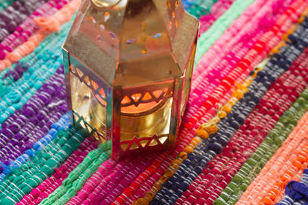 Gold candle on a colorful fabric table.の写真素材