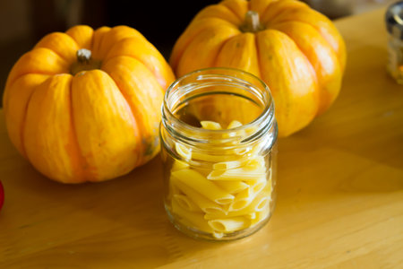 dry pasta in glass and pumpkin on wood .の写真素材