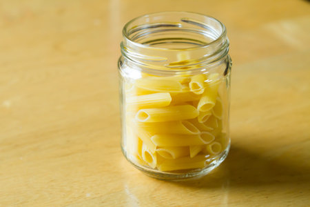 dry pasta in glass and pumpkin on wood .の写真素材