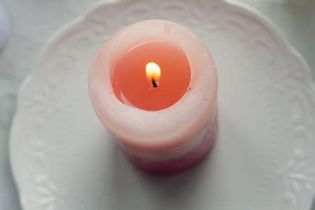 pink candle on a white table .の写真素材
