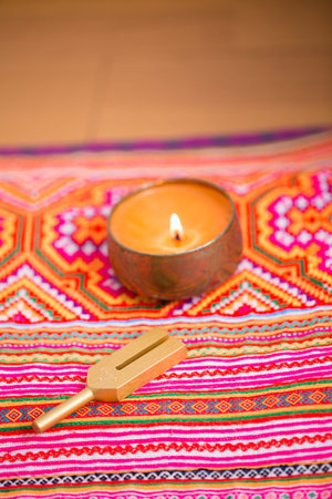 Candle and traditional thai style rug on wooden table. Selective focus.の写真素材