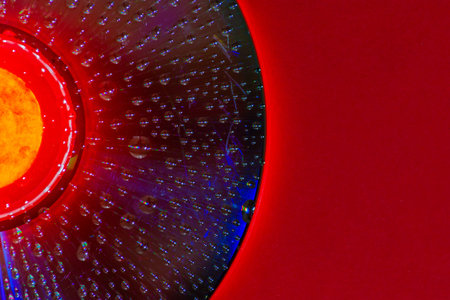 Water drops on a CD with a red background の写真素材