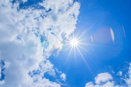 Blue sky with clouds and sun emitting radius の写真素材