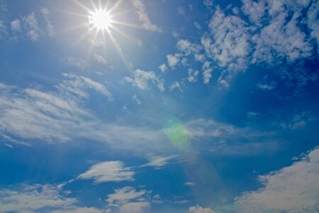 Blue sky with clouds and sun shining の写真素材