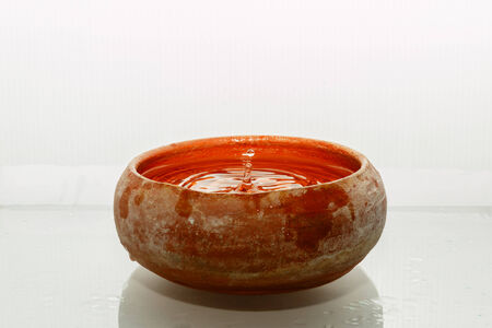 Drops of water in a clay pot on a white background の写真素材