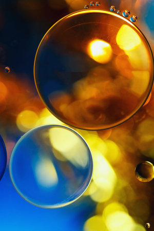 close up oil floating on water with yellow blue background