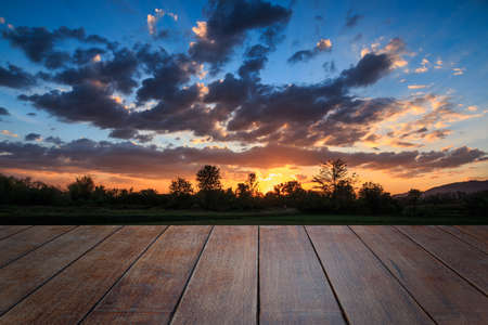 The empty wooden board on a background sky with sunset in fieldsの写真素材